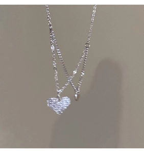 Macro detail of a silver double-layered heart bracelet with pavé-set shimmering cubic zirconia