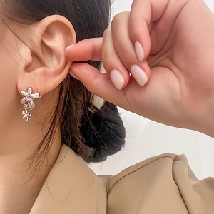 Détail de boucles d'oreilles fleurs en argent avec zircons roses portées par un mannequin