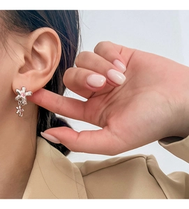 Gros plan de boucles d'oreilles fleurs avec pierre rose portée avec un blazer beige