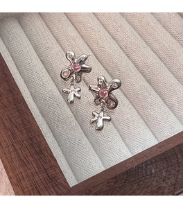 Vue rapprochée de boucles d'oreilles fleurs en argent avec zircons roses sur plateau gris