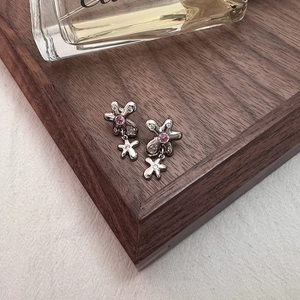 Détail de boucles d'oreilles fleur avec zircon rose et diamants sur plateau bois