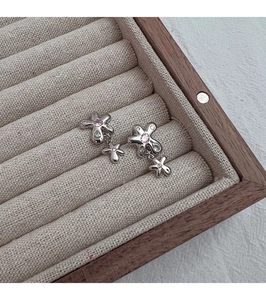 Détail des boucles d'oreilles fleurs argentées avec zircons roses en boîte à bijoux