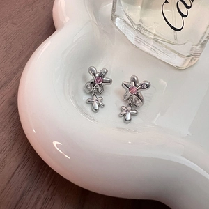 Boucles d'oreilles fleur argentées avec pierre rose et cristaux dans un plateau cœur