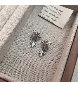 Gros plan de boucles d'oreilles fleurs en argent avec pierres roses dans une boîte à bijoux