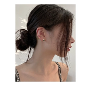 Gros plan d'une créole dorée et d'un clou d'oreille carré en zircon noir sur un mannequin