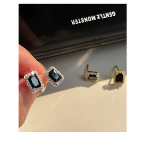 Vue macro de boucles d'oreilles carrées en zircon noir avec bordure en argent sur les doigts