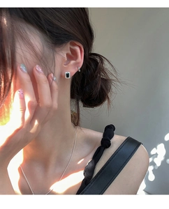 Gros plan sur des boucles d'oreilles carrées en zircon noir avec halo de cristaux brillants
