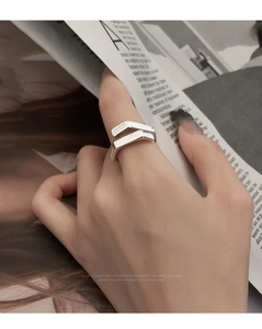 Close-up of minimalist geometric silver ring worn on hand with fashion magazine backdrop