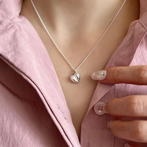 Collier à pendentif cœur 3D minimaliste en métal argenté poli porté par un modèle