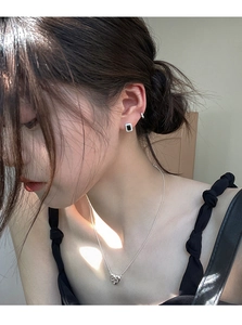 Gros plan sur le collier cœur et les boucles d'oreilles carrées en zircon noir sur modèle