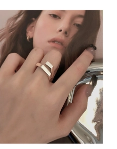 Close-up of minimalist silver open ring with overlapping geometric design worn on finger