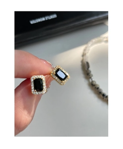 Vue macro de boucles d'oreilles en zircon noir avec finition dorée et détails de halo
