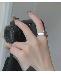 Detailed view of a minimalist silver square-band open ring on model holding a camera