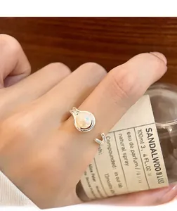 Close-up of double layer silver ring with white pearl and H letter on woman's hand
