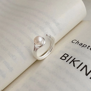 Elegant double-layered silver open ring with a round pearl on a minimalist book background