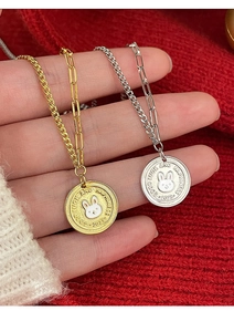 Detailed shot of rabbit pendant necklace featuring good luck engraving on red knit background