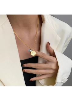 Detailed view of a gold bunny coin necklace with Good Luck engraving on a model