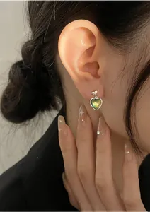 Detailed view of heart-shaped cat-eye stone earrings with bow detail on female model
