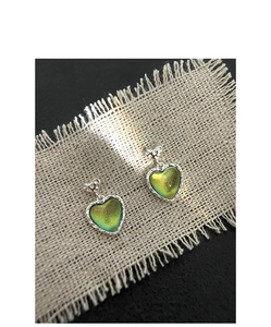 Close-up of heart-shaped cat-eye stud earrings with hammered metal texture on linen