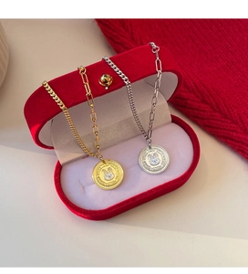 Close-up of gold and silver rabbit coin pendants on elegant red velvet gift box