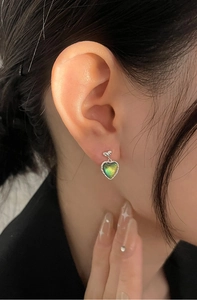 Detail of aurora heart stud earring with silver bear accent on model's ear