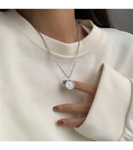 Macro detail of silver rabbit pendant necklace with Good Luck engraving on sweater