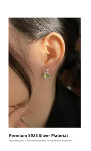 Model wearing S925 silver heart stud earrings with green cat eye stone detail