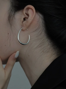 Orecchini a cerchio ovali geometrici in argento lucido indossati da una modella elegante