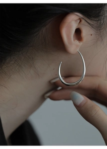 Primo piano di un orecchino a cerchio a goccia geometrico argento su modella con finitura