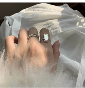 Detailed view of silver rings featuring geometric design and opal-like stone inlay