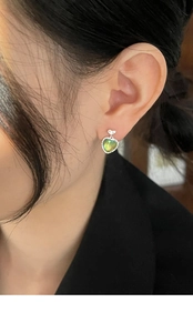 Close-up of Aurora cat-eye heart earrings worn by a model in a natural setting