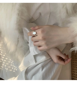 Close-up of elegant silver shell ring with white rectangular stone on a model hand