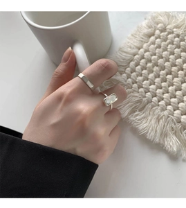 Close-up of a minimalist silver shell ring set featuring a sleek band and a mother of pearl stone