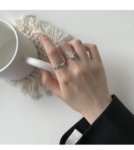 Detail of silver shell ring and minimalist band on hand with elegant aesthetic