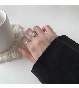 Detail view of silver shell ring and geometric band on model hand with minimalist style