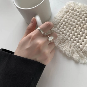 Elegant silver shell ring set with minimalist wide band shown in a lifestyle hand-held setting