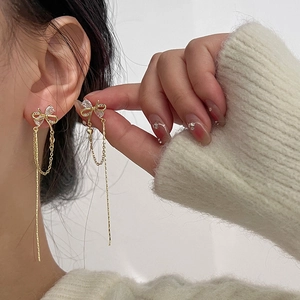 Close-up of elegant gold bow tassel earrings with sparkling crystals worn by a model