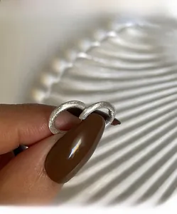 Dettaglio di orecchini a cerchio in argento spazzolato opaco con texture minimalista