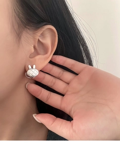 Gros plan de boucles d'oreilles lapin en argent S925 avec texture matelassée sur le mannequin