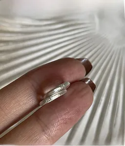 Dettaglio di un anello in argento opaco con finitura spazzolata e design avvolgente minimal