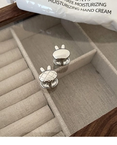 Gros plan sur des boucles d'oreilles lapin en argent S925 avec texture lisse et quadrillée