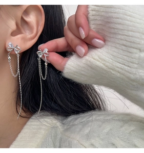 Detail of French bow tassel earrings with white zircon stones on long silver chains