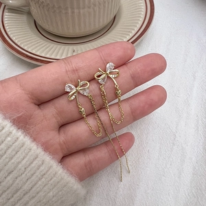 Elegant gold bow tassel earrings with zircon heart charm on a minimalist background