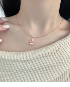 Close-up of pink cat eye stone bunny pendant necklace in rose gold finish on model