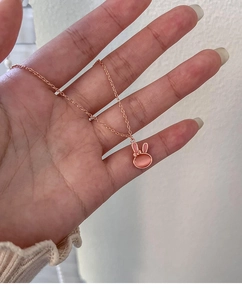 Detailed close-up of rose gold rabbit pendant with pink cat eye stone and bow knot