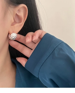 Gros plan d'une boucle d'oreille météore argentée avec texture martelée sur l'oreille