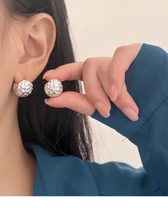 Détail de boucles d'oreilles argentées à texture lave portées par un mannequin