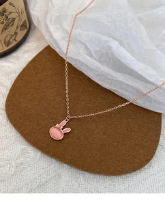 Close-up of pink cat eye stone rabbit necklace with rose gold bow detail