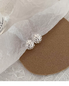 Détail des boucles d'oreilles lave argentées avec fini martelé minimaliste et éclat métallique