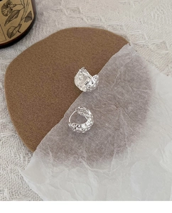 Détail macro des boucles d'oreilles lave argentée avec texture martelée sur tissu chaud